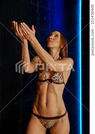 Adult sporty woman in bikini catch water drops in indoor public pool shower Adult sporty woman in bikini catch water drops in indoor public pool shower 101436406