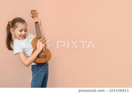 Expressive Caucasian girl of primary school age with a children's guitar or ukulele like a rock star, copy space Expressive Caucasian girl of primary school age with a children's guitar or ukulele like a rock star, copy space 101436911