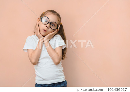 Cute surprised little caucasian girl in round glasses and hands near her face on a pink background with empty space Cute surprised little caucasian girl in round glasses and hands near her face on a pink background with empty space 101436917