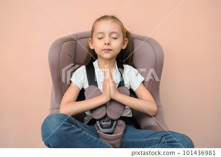 Funny happy caucasian girl of primary school age feels calm and safe in a car seat 101436981