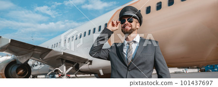 Cheerful aircraft pilot standing outdoors at airport 101437697