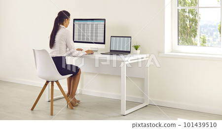 Young business woman accountant working on a laptop with tables at modern white office. Young business woman accountant working on a laptop with tables at modern white office. 101439510