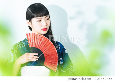 A woman wearing a yukata and holding a folding fan 101439836