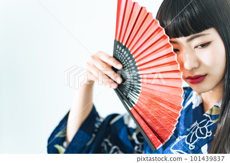 A woman wearing a yukata and holding a folding fan 101439837