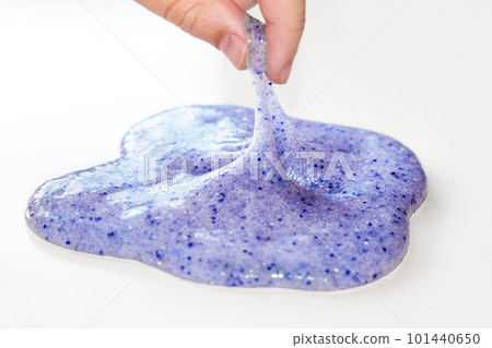 Playing with textured slime with bubbles, stretching the gooey substance. Female teen hand holding blue shining slime, squeezing it. Liquid toy. 101440650