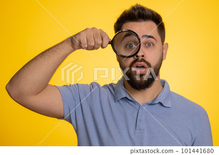 Investigator researcher man with magnifying glass near face, looking into camera with big zoom eye 101441680