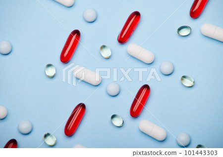 Flat lay. Background of medical pills, red translucent gel capsules and dragee laid out in pattern on isolated blue background. Antidepressant therapy. Painkiller. Pharma business and industry concept Flat lay. Background of medical pills, red translucent gel capsules and dragee laid out in pattern on isolated blue background. Antidepressant therapy. Painkiller. Pharma business and industry concept 101443303