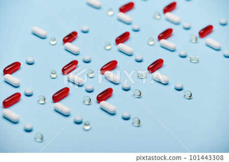 Medical background with red gelatin translucent capsules with essential oils, Omega 3 or fat-soluble vitamins and pharmaceutical pills laid out in pattern on blue surface. Pharma industry and business Medical background with red gelatin translucent capsules with essential oils, Omega 3 or fat-soluble vitamins and pharmaceutical pills laid out in pattern on blue surface. Pharma industry and business 101443308