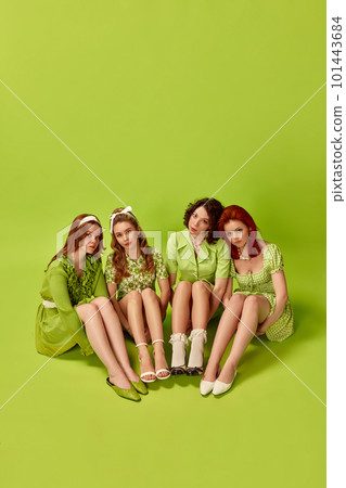 Top view. Portrait of pretty, stylish young women, friends posing against green studio background. Retro fashion, pin-up, 60s 101443684