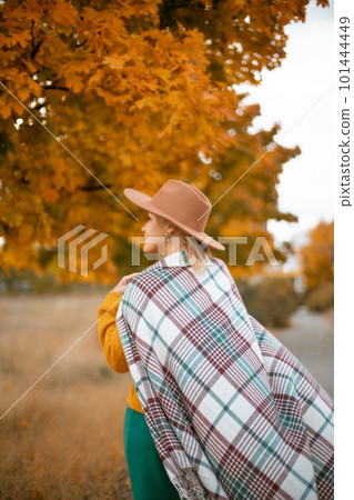 autumn woman in a green dress, brown hat, plaid, against the background of an autumn tree autumn woman in a green dress, brown hat, plaid, against the background of an autumn tree 101444449