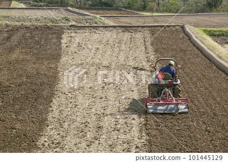 Take a picture of the landscape of the field being cultivated with a tractor 101445129
