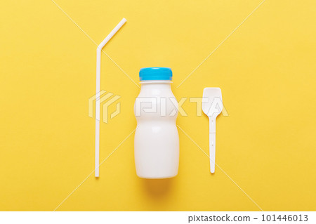 Three subjects isolated over yellow background, bottle from milk or yogurt, plastic spoon and straw, using plastics, diary product in white bottle with blue cap. 101446013