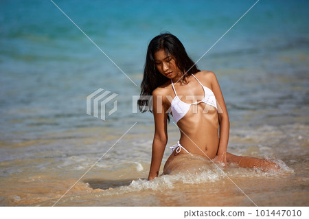 Beautiful asian girl in white bikini posing at the tropical beach Beautiful asian girl in white bikini posing at the tropical beach 101447010