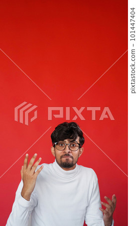 Annoyed face. Angry shrug. Stress frustration. Portrait of mad displeased man in glasses outraging on red color empty space background. Annoyed face. Angry shrug. Stress frustration. Portrait of mad displeased man in glasses outraging on red color empty space background. 101447404