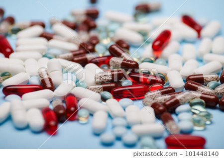 Background of multi-colored medical pills, tablets, dragees and translucent gel capsules, scattered on blue background. Close-up. Still life. Pharma business. Pharmaceutical industry. World Health Day Background of multi-colored medical pills, tablets, dragees and translucent gel capsules, scattered on blue background. Close-up. Still life. Pharma business. Pharmaceutical industry. World Health Day 101448140