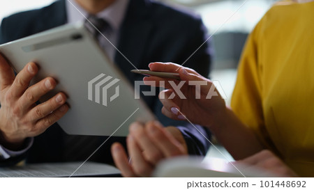 Team of business partners studying information on digital tablet at meeting closeup 101448692