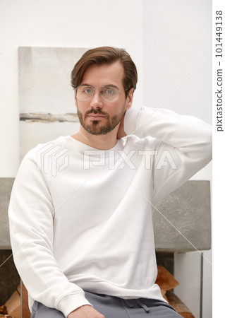 Close-up of a cheerful satisfied attractive man with stubble, with a wide smile, in round glasses, rejoices at success at work, stands against the backdrop of a cozy interior. Fashion designer happy Close-up of a cheerful satisfied attractive man with stubble, with a wide smile, in round glasses, rejoices at success at work, stands against the backdrop of a cozy interior. Fashion designer happy 101449138