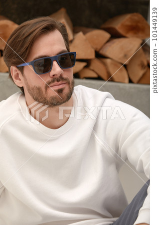 Close-up of a cheerful satisfied attractive man with stubble, with a wide smile, in round glasses, rejoices at success at work, stands against the backdrop of a cozy interior. Fashion designer happy 101449139