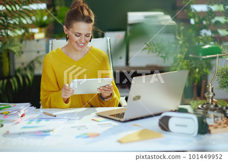 happy business owner woman in green office using tablet PC 101449952
