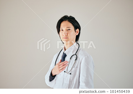 A young man in a white coat standing with his hands on his chest A young man in a white coat standing with his hands on his chest 101450439