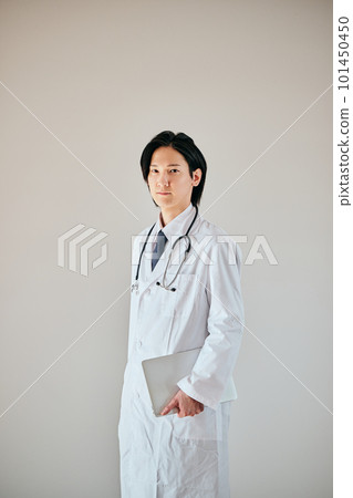 A young man in a white coat standing with a personal computer A young man in a white coat standing with a personal computer 101450450