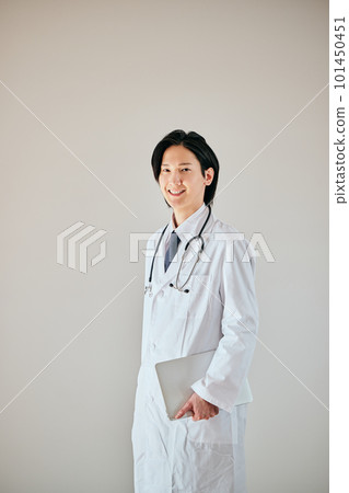 A young man in a white coat standing with a personal computer A young man in a white coat standing with a personal computer 101450451