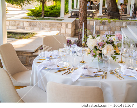 Wedding banquet concept. Chairs and round table for guests, served with cutler and, flowers and crockery and covered with a tablecloth Wedding banquet concept. Chairs and round table for guests, served with cutler and, flowers and crockery and covered with a tablecloth 101451167