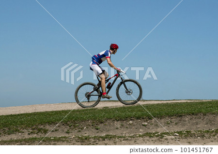 athlete cyclist riding mountain bike on hill in background blue sky, cross-country cycling 101451767