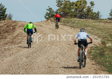 rear view three mountainbikers riding bike uphill, biking on gravel road, cycling competition rear view three mountainbikers riding bike uphill, biking on gravel road, cycling competition 101451783