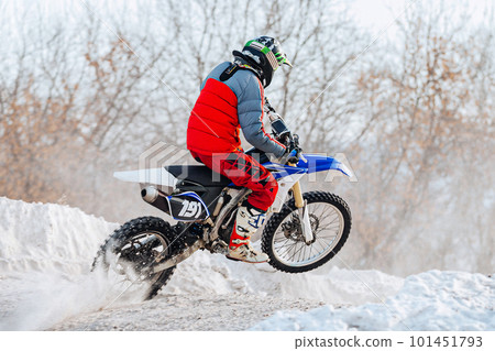 motocross rider riding winter off-road motorcycle racing, snow splashes from under rear wheel motocross rider riding winter off-road motorcycle racing, snow splashes from under rear wheel 101451793