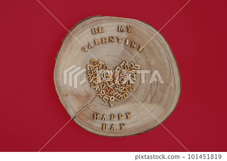 Alphabet letters on wooden square pieces forming heart shape on red background 101451819
