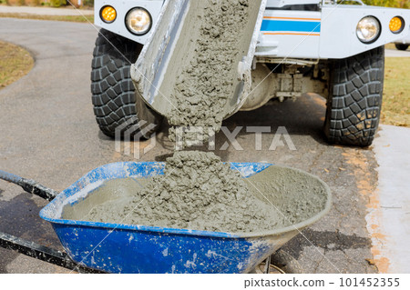 Mixer truck pours concrete into wheelbarrow at construction site Mixer truck pours concrete into wheelbarrow at construction site 101452355
