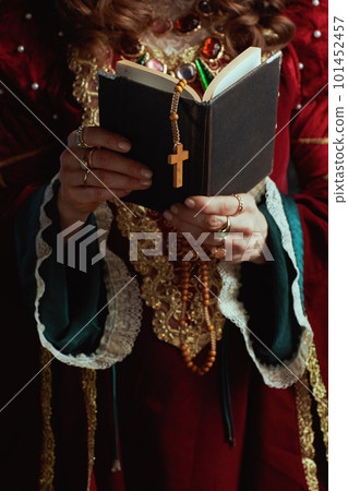 Closeup on medieval queen in red dress with book and rosary Closeup on medieval queen in red dress with book and rosary 101452457