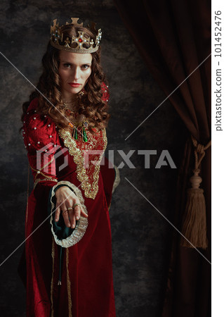 medieval queen in red dress with crown making reverence 101452476