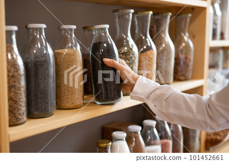 Woman in a store selling cereals by weight in an eco store. Trade concept without plastic packaging Woman in a store selling cereals by weight in an eco store. Trade concept without plastic packaging 101452661