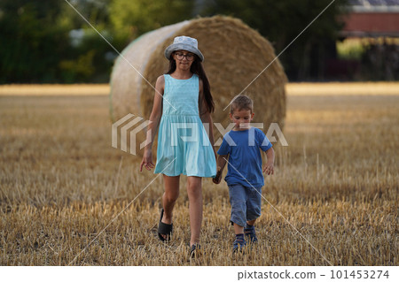 Two Children brother and sister on a hay field at the sunset. Two Children brother and sister on a hay field at the sunset. 101453274