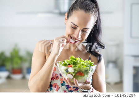 Healthy lifestyle young woman eating lettuce salad. Young brunette eating healthy food in her kitchen Healthy lifestyle young woman eating lettuce salad. Young brunette eating healthy food in her kitchen 101453294