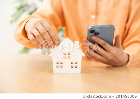 A woman thinking about buying a house with a smartphone A woman thinking about buying a house with a smartphone 101453309