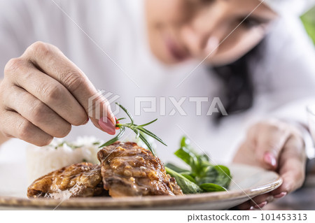 Close-up view of chef's fingers with rosemary sprig decorating food in restaurant kitchen Close-up view of chef's fingers with rosemary sprig decorating food in restaurant kitchen 101453313