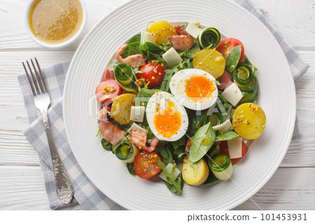 French peasant salad or salade paysanne with lettuce, bacon, cheese, tomatoes, potatoes and soft-boiled eggs closeup. Horizontal top view 101453931