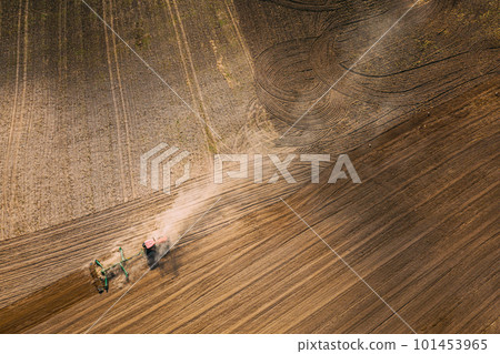 Aerial View. Tractor Plowing Field. Beginning Of Agricultural Spring Season. Cultivator Pulled By A Tractor In Countryside Rural Field Landscape. Dust Rises From Under Plows Aerial View. Tractor Plowing Field. Beginning Of Agricultural Spring Season. Cultivator Pulled By A Tractor In Countryside Rural Field Landscape. Dust Rises From Under Plows 101453965