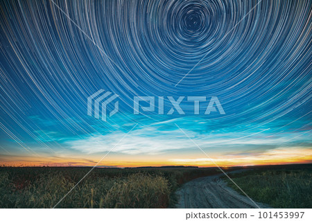 Morning Sunrise In Countryside. Unusual Amazing Effect Of Cloud And Stars Trails Above Countryside Rural Field Landscape With Young Green Wheat Sprouts In Springtime. Soft Colors 101453997