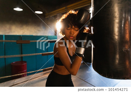 Women self defense girl power. African american woman fighter resting after fight training on boxing ring. Girl tired after punching boxing bag. Training day in gym. Strength fit body workout training Women self defense girl power. African american woman fighter resting after fight training on boxing ring. Girl tired after punching boxing bag. Training day in gym. Strength fit body workout training 101454271