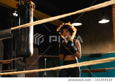 Women self defense girl power. African american woman fighter training punches on boxing ring. Healthy strong girl punching boxing bag. Training day in boxing gym. Strength fit body workout training 101454319