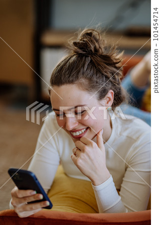 Young woman scrolling her smartphone in the apartment. Young woman scrolling her smartphone in the apartment. 101454714