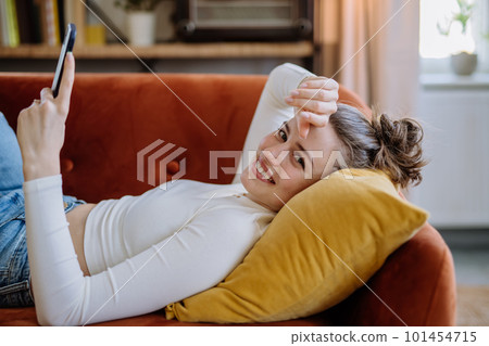 Young woman scrolling her smartphone in the apartment. Young woman scrolling her smartphone in the apartment. 101454715