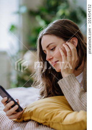 Young woman scrolling her smartphone in the apartment. Young woman scrolling her smartphone in the apartment. 101454732
