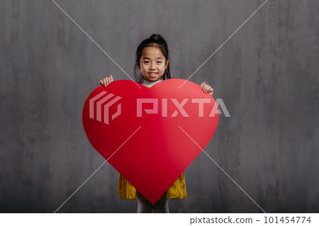 Little girl holding model of heart, studio photography. 101454774