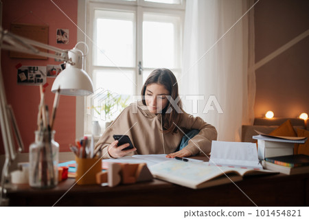 Young teenage girl studying in her room. 101454821
