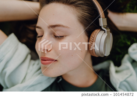 Portrait of young woman listening music trough headphones. Portrait of young woman listening music trough headphones. 101454872
